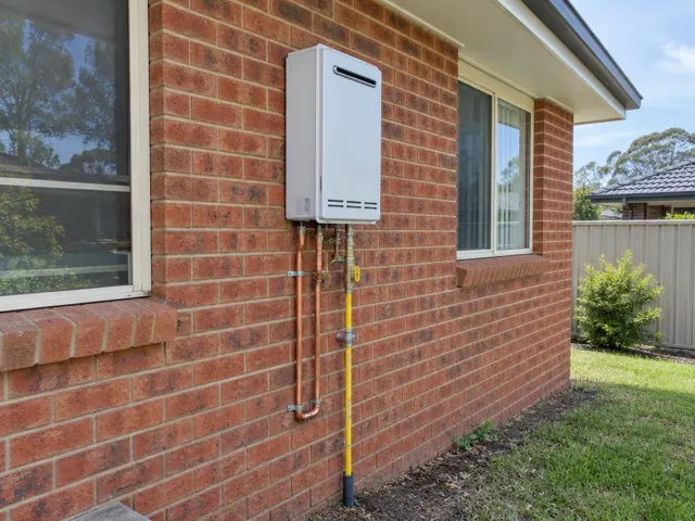 Wall-mounted hot water system on a brick house exterior with exposed pipework in Windale